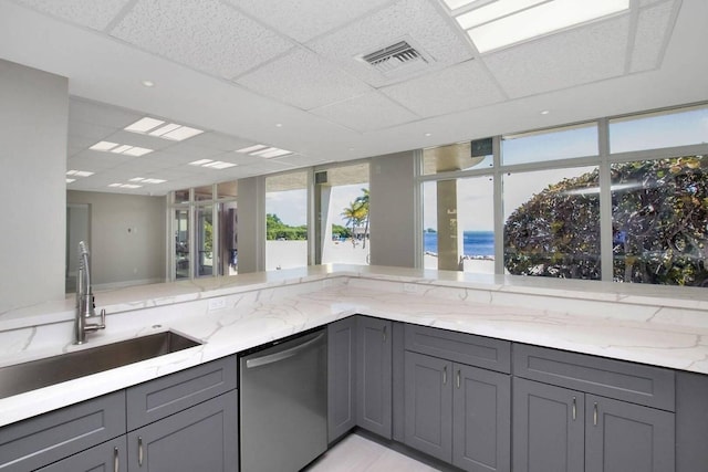 kitchen featuring dishwasher, sink, gray cabinetry, and light stone counters