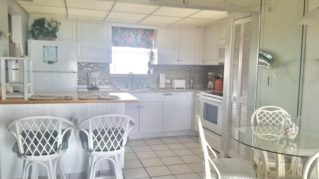 kitchen with white appliances, sink, decorative backsplash, and white cabinets