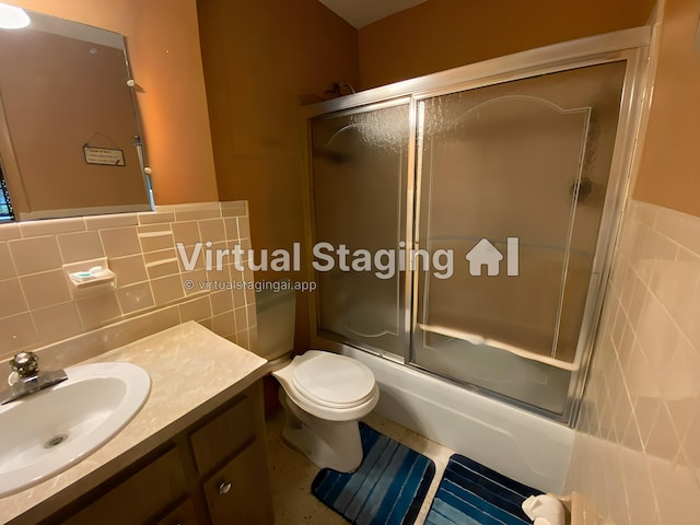 full bathroom featuring vanity, tile walls, shower / bath combination with glass door, and toilet