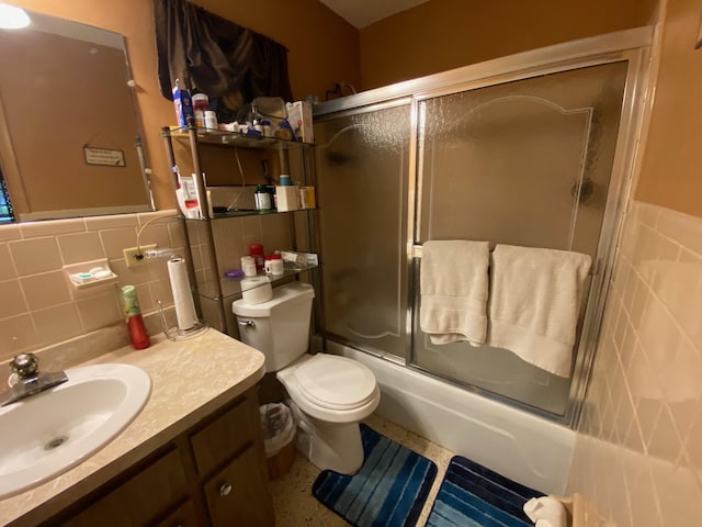 full bathroom featuring enclosed tub / shower combo, vanity, toilet, and tile walls