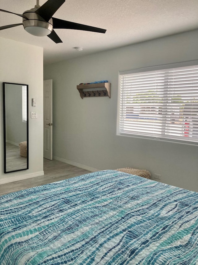 bedroom featuring ceiling fan, hardwood / wood-style floors, and a textured ceiling