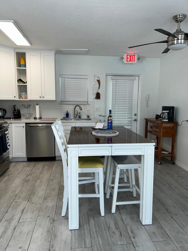 kitchen featuring sink, white cabinetry, tasteful backsplash, a kitchen bar, and stainless steel dishwasher