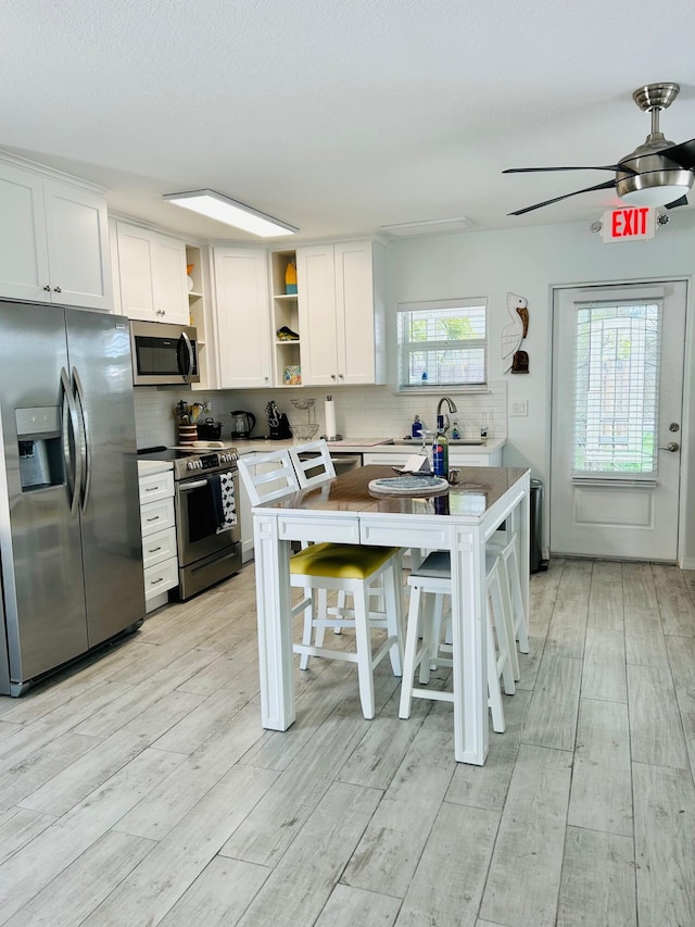 kitchen with white cabinetry, appliances with stainless steel finishes, a breakfast bar, and tasteful backsplash