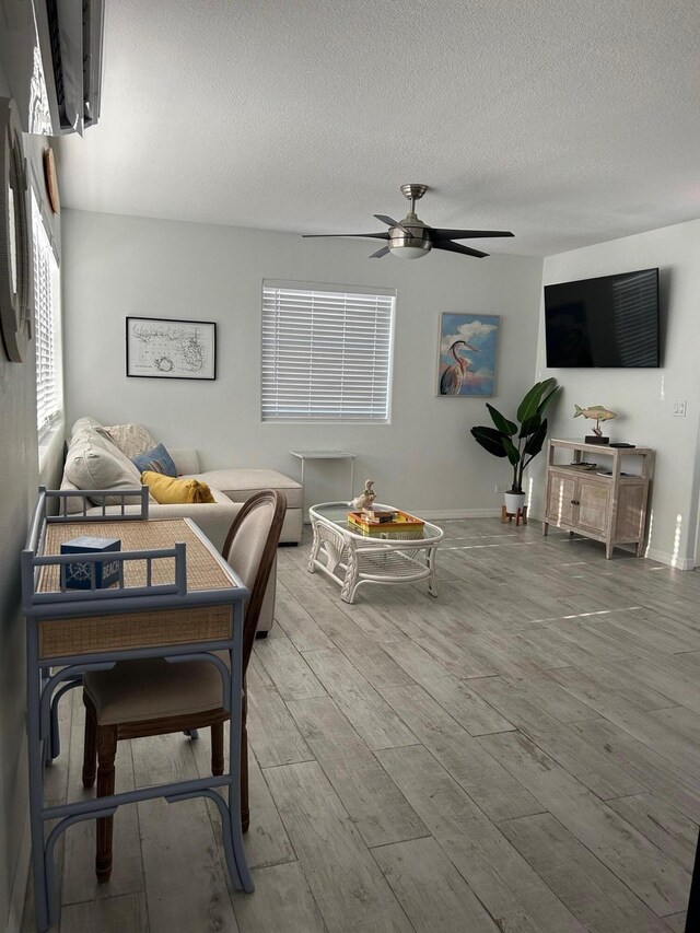 living room with hardwood / wood-style floors, a textured ceiling, and ceiling fan