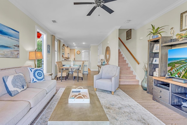 living room with crown molding, ceiling fan, and light hardwood / wood-style floors