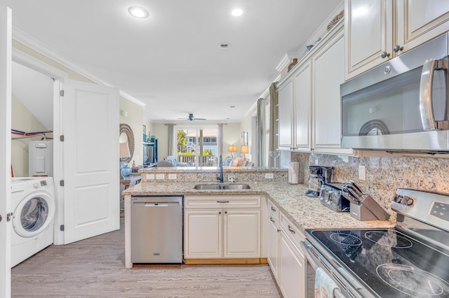 kitchen with washer / clothes dryer, sink, ornamental molding, kitchen peninsula, and stainless steel appliances