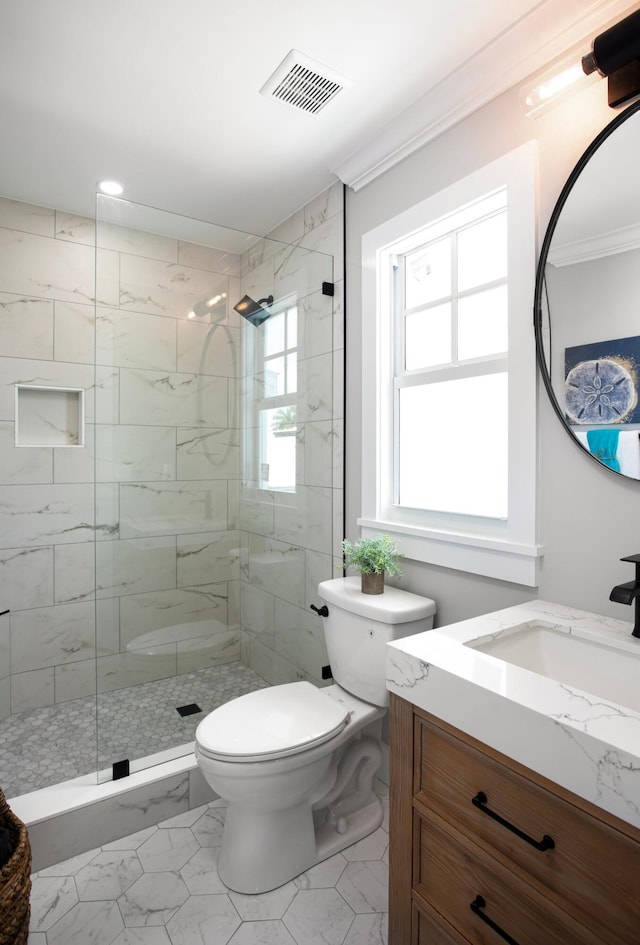 bathroom with vanity, ornamental molding, tiled shower, and toilet