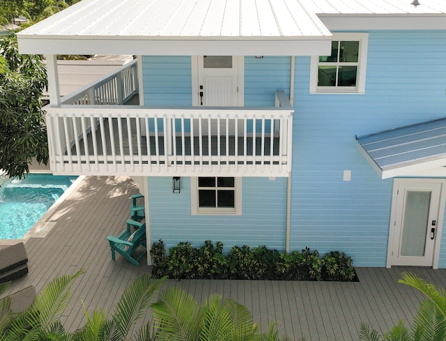 back of property with a wooden deck and a balcony