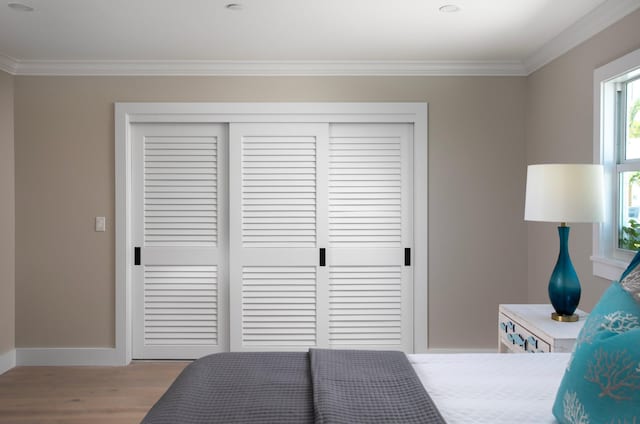 bedroom featuring crown molding, a closet, and light wood-type flooring