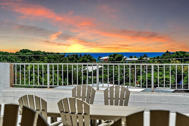 balcony at dusk featuring a water view