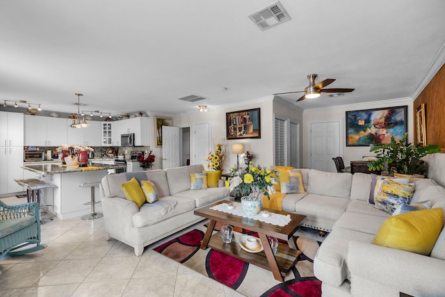 living room featuring ornamental molding, a ceiling fan, visible vents, and light tile patterned flooring