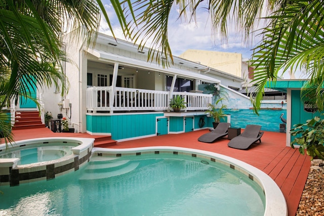 view of swimming pool featuring a deck and a pool with connected hot tub