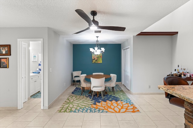 dining room with visible vents, ceiling fan with notable chandelier, a textured ceiling, light tile patterned floors, and baseboards