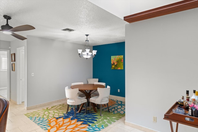 dining space with tile patterned floors, visible vents, ceiling fan with notable chandelier, a textured ceiling, and baseboards