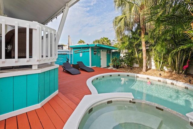 view of swimming pool featuring a wooden deck and a pool with connected hot tub