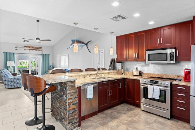 kitchen with visible vents, appliances with stainless steel finishes, a kitchen breakfast bar, a peninsula, and a sink