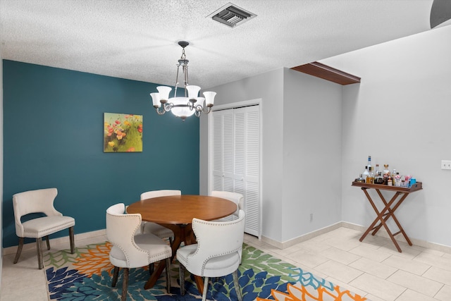 dining area with visible vents, a textured ceiling, light tile patterned floors, baseboards, and a chandelier