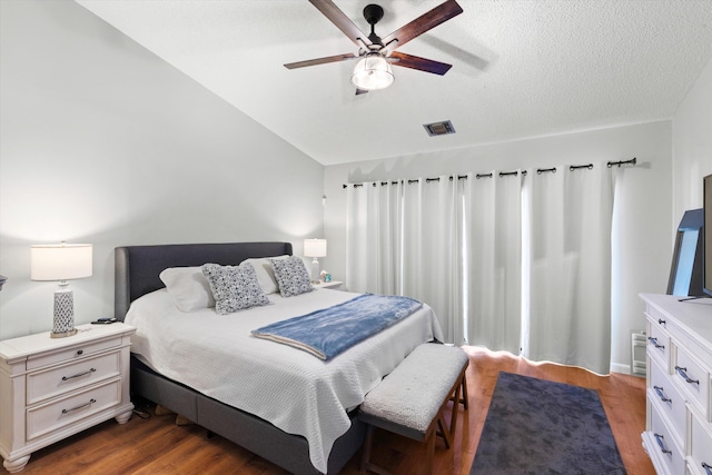 bedroom featuring visible vents, dark wood-type flooring, a ceiling fan, a textured ceiling, and vaulted ceiling