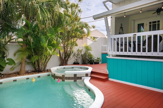 view of swimming pool featuring ceiling fan, fence, a pool with connected hot tub, and a wooden deck