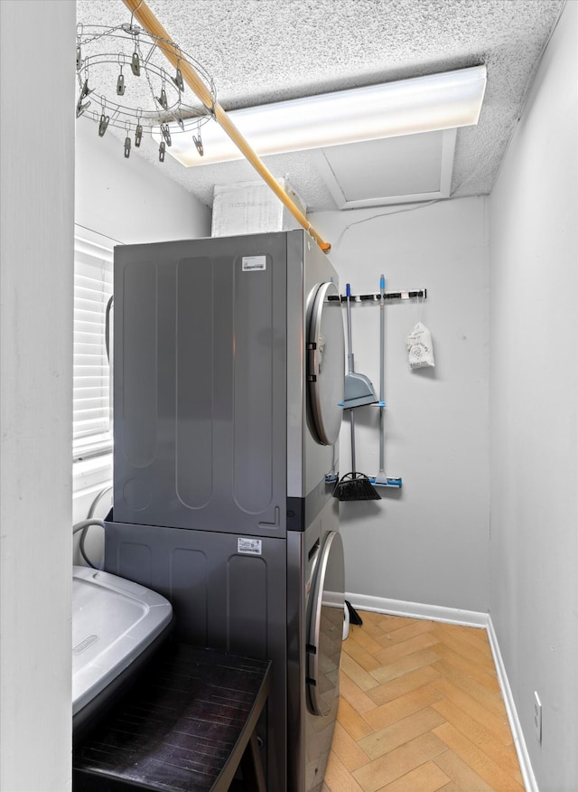 laundry area with laundry area, a textured ceiling, baseboards, and stacked washer and dryer