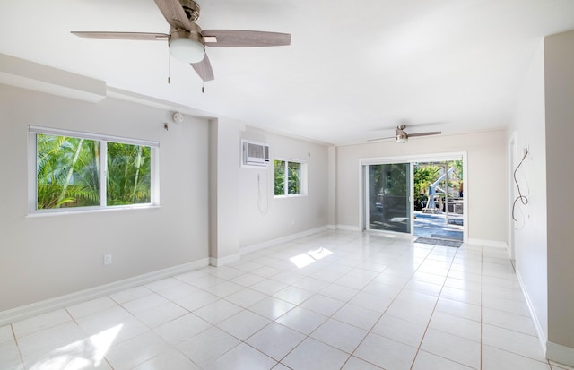 empty room featuring light tile patterned flooring, ceiling fan, an AC wall unit, and baseboards