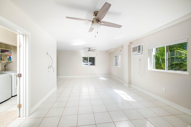 empty room featuring a wall unit AC, baseboards, light tile patterned flooring, ceiling fan, and independent washer and dryer