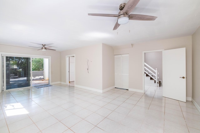 spare room featuring stairs, light tile patterned flooring, baseboards, and ceiling fan