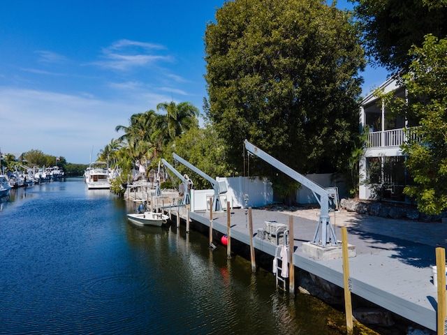 view of dock featuring a water view, boat lift, and fence