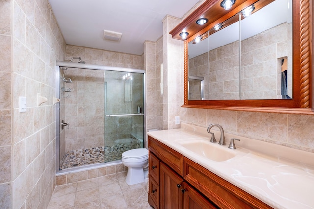 bathroom with vanity, tile walls, toilet, and a stall shower