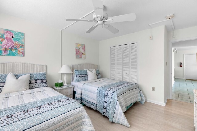 bedroom with light hardwood / wood-style flooring, ceiling fan, and a closet