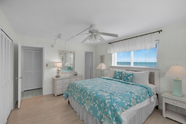 bedroom featuring ceiling fan, a water view, and light hardwood / wood-style floors