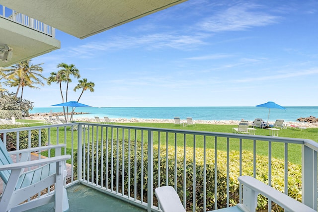 balcony with a water view and a view of the beach