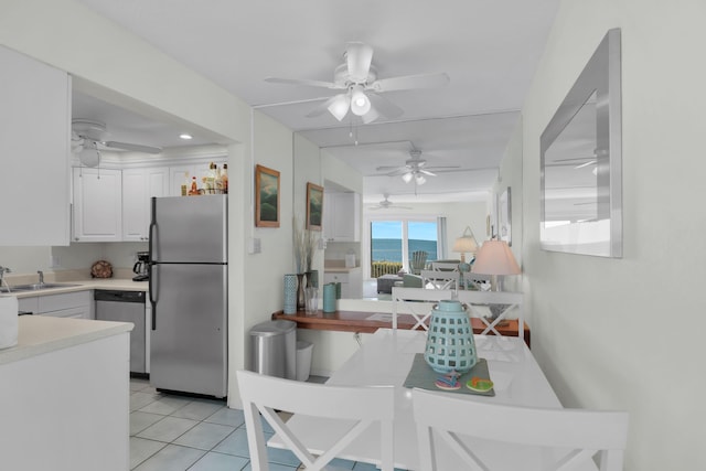 kitchen with stainless steel appliances, sink, light tile patterned floors, and white cabinets