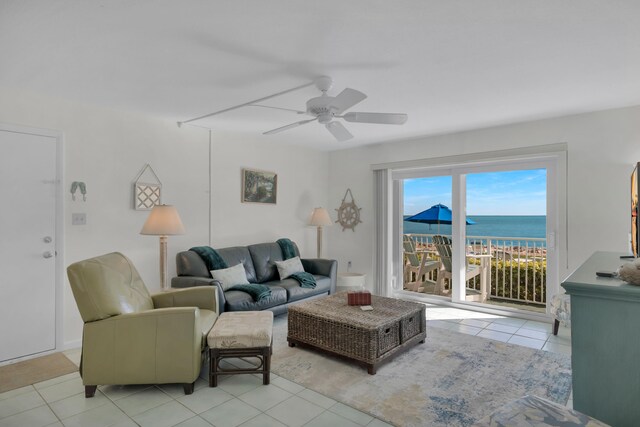 tiled living room with ceiling fan and a water view