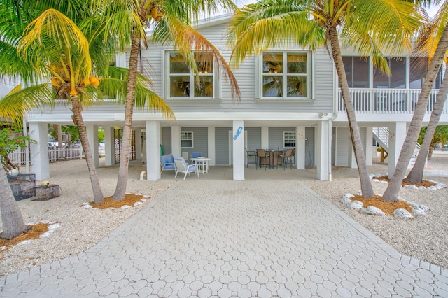 rear view of property featuring a carport, decorative driveway, a patio, and stairs