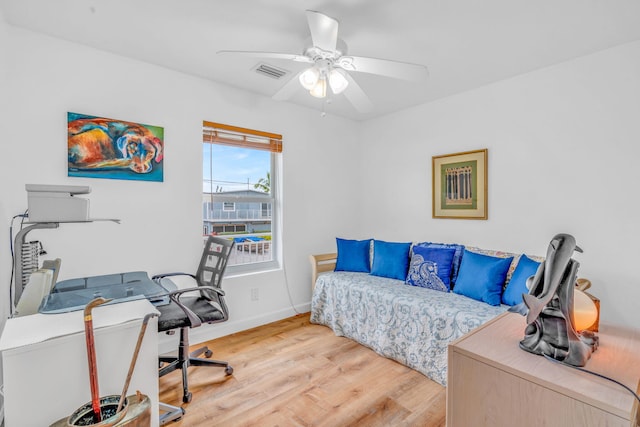 bedroom featuring a ceiling fan, visible vents, baseboards, and wood finished floors