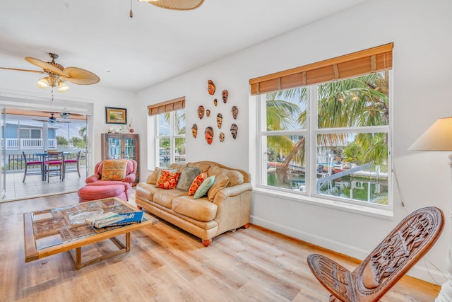 living room with ceiling fan, baseboards, and wood finished floors