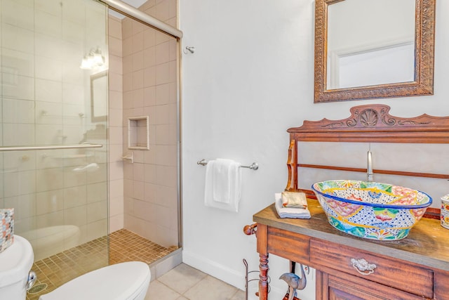 bathroom with toilet, a stall shower, tile patterned flooring, and baseboards