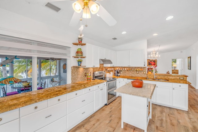 kitchen with under cabinet range hood, a peninsula, a sink, vaulted ceiling, and double oven range