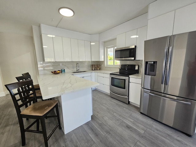 392 Laguna Ave, Key Largo, FL 33037 - kitchen featuring stainless steel appliances, modern cabinets, a sink, a breakfast bar area, and white cabinets