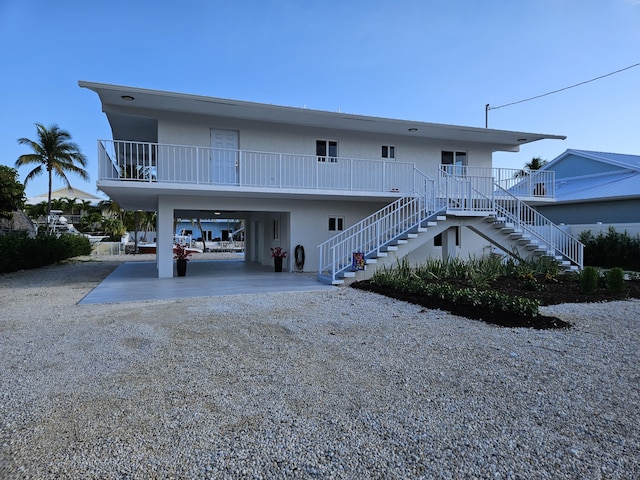 392 Laguna Ave, Key Largo, FL 33037 - rear view of property featuring a carport, stairway, stucco siding, and driveway