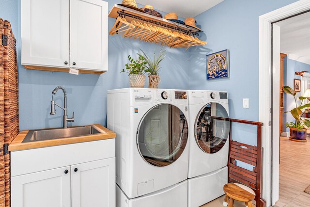 laundry area with cabinets, washer and clothes dryer, and sink