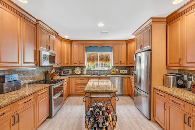 kitchen featuring sink, light stone countertops, a center island, and appliances with stainless steel finishes