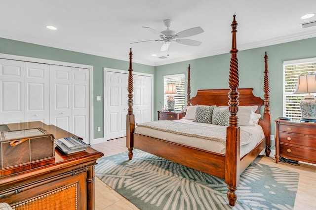 bedroom featuring ornamental molding, two closets, and ceiling fan