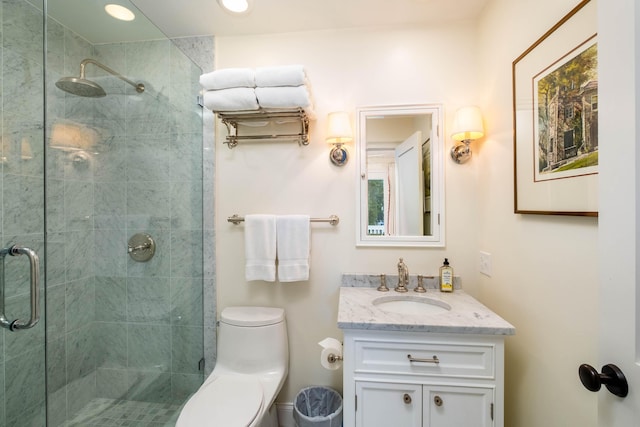 bathroom featuring vanity, a shower with shower door, and toilet