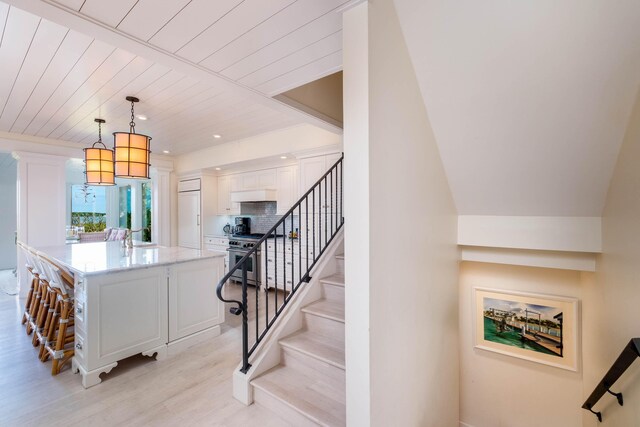 stairs featuring hardwood / wood-style floors, wood ceiling, and sink