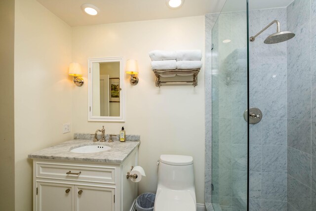 bathroom featuring tiled shower, vanity, and toilet