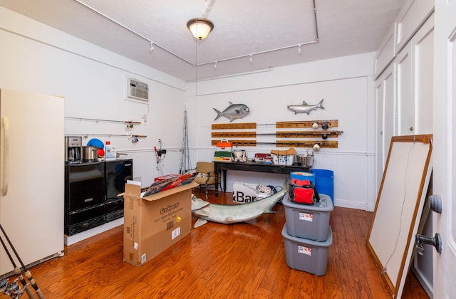 miscellaneous room featuring rail lighting, a wall mounted air conditioner, and hardwood / wood-style floors