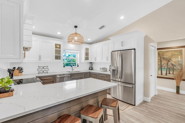 kitchen featuring white cabinetry, appliances with stainless steel finishes, kitchen peninsula, pendant lighting, and light stone countertops