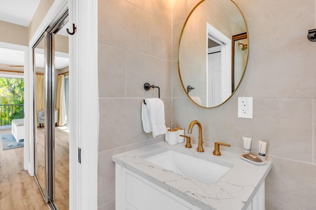 bathroom featuring tile walls, vanity, wood-type flooring, and tasteful backsplash